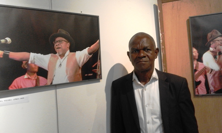 Le photographe Kokolo posant à côté de sa photo favorite 