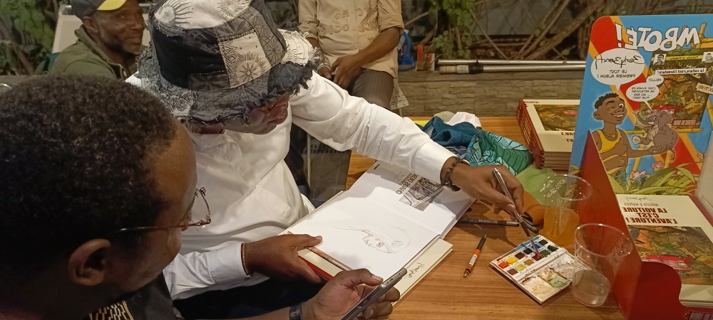 1 : Barly Baruti fait une dédicace à l’aquarelle au Memling / Adiac 1 : Barly Baruti fait une dédicace à l’aquarelle au Memling / Adiac