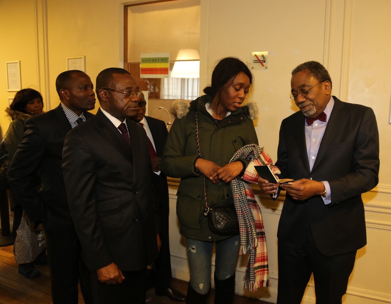 Rodolphe Adada, Amabassadeur du Congo en France admirant un passeport biométrique remis à une compatriote au consulat de Paris