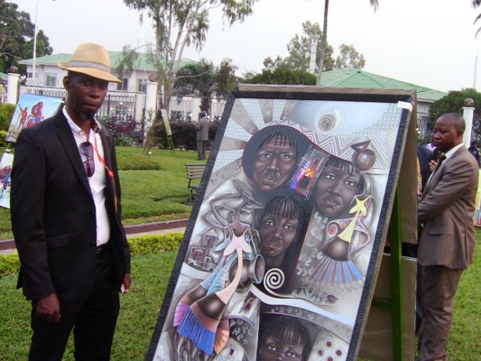 Mbikulu posant à côté de sa peinture 